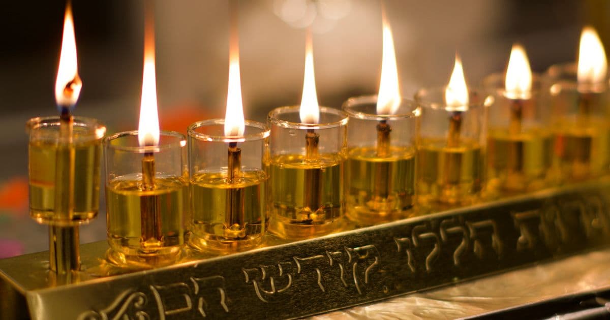 Row of lit Hanukkah candles glowing in a menorah