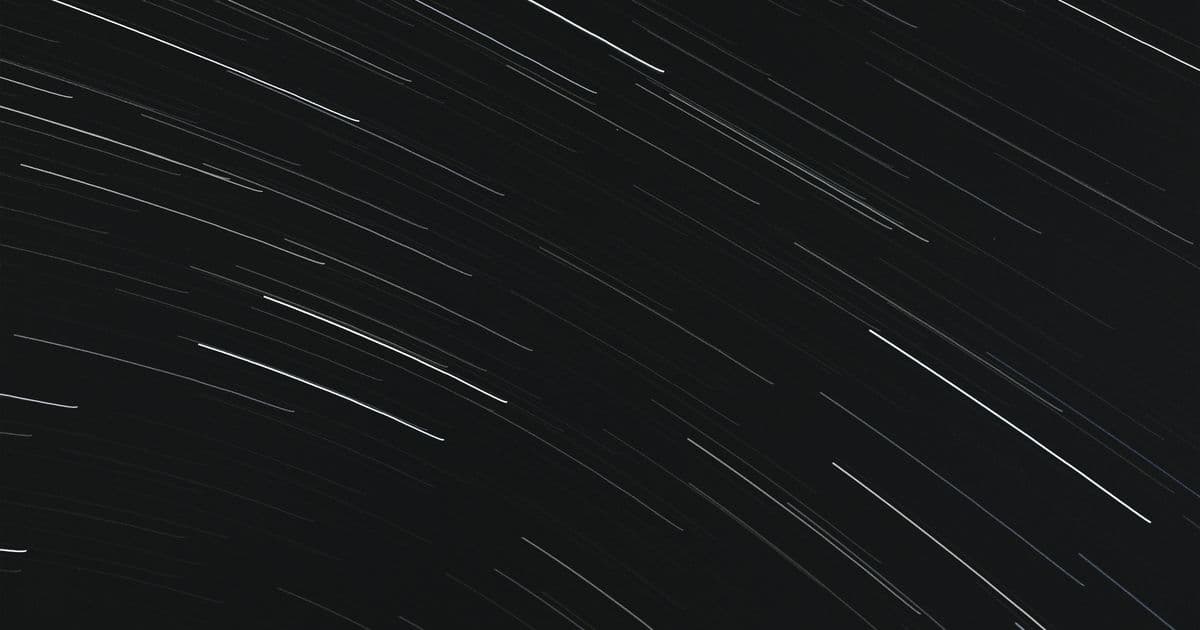 Long-exposure star trails arcing across a dark navy night sky