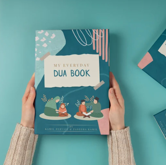 Childs hands holding My Everyday Dua Book with illustrations of children