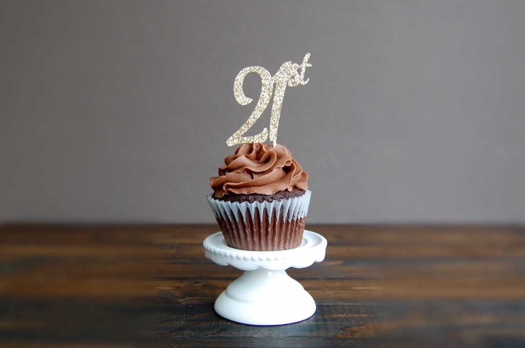 A chocolate cupcake topped with a glittery 21st cake topper