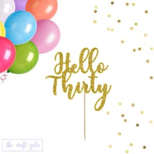 Gold glitter 'Hello Thirty' cake topper surrounded by colorful balloons