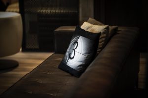 Illuminated pillow with a number 3 design on a leather couch in a dim man cave