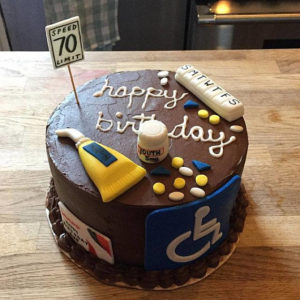 Chocolate over-the-hill birthday cake decorated with a cane, a speed limit 70 sign, and a handicap symbol