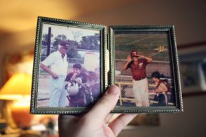 Hand holding open a small photo album displaying two old family photographs
