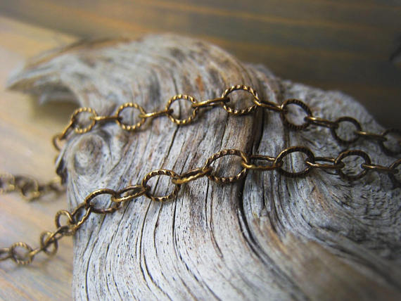 Close-up of an antique gold chain draped over weathered wood