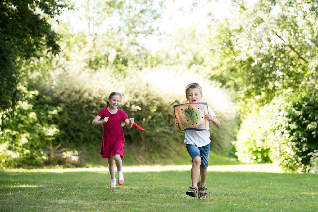 Two children running outdoors with a scavenger hunt game board