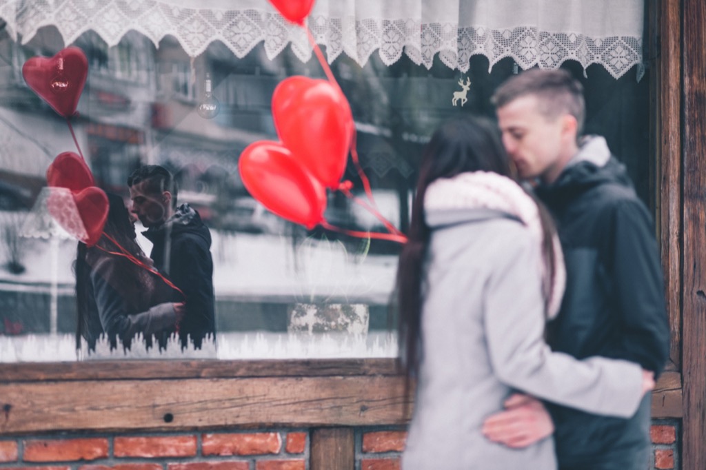 Red heart-shaped balloons framing a couple embracing