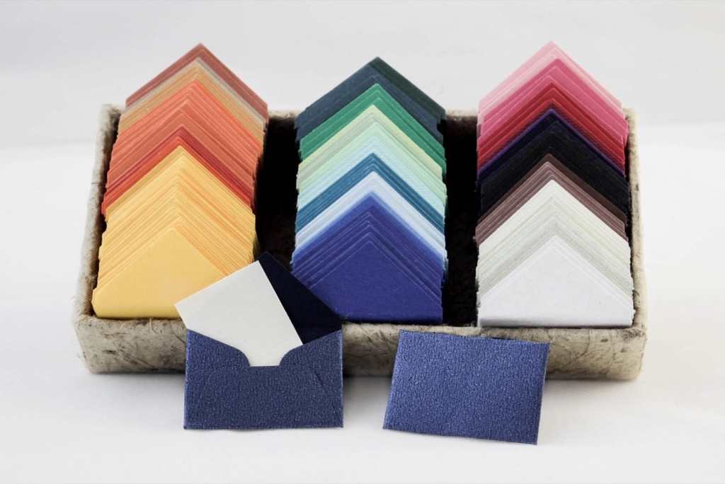 A tray of colorful paper card stock and small envelopes