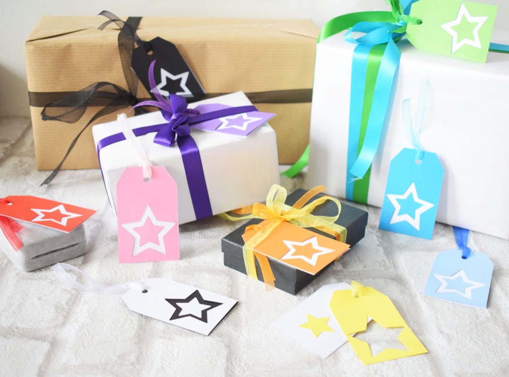 Small wrapped presents with star gift tags in a colorful pile