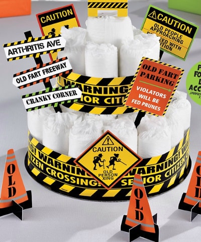 A diaper cake decorated with 'Old Fart Freeway,' 'Cranky Corner,' and other caution-sign party picks
