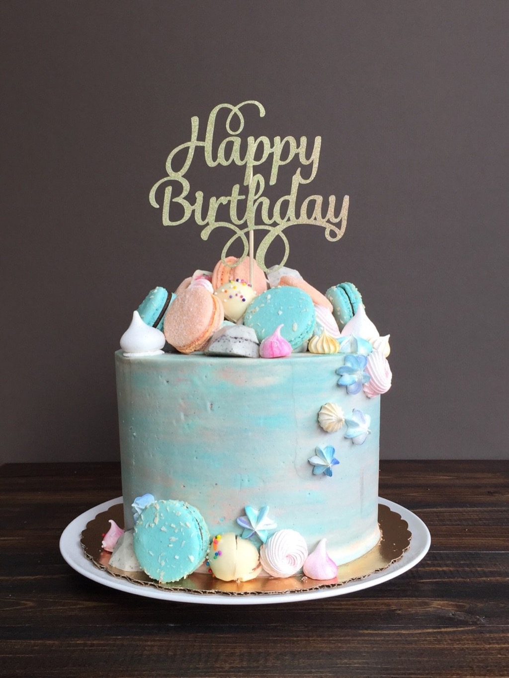 Happy birthday cake topped with macarons and meringues