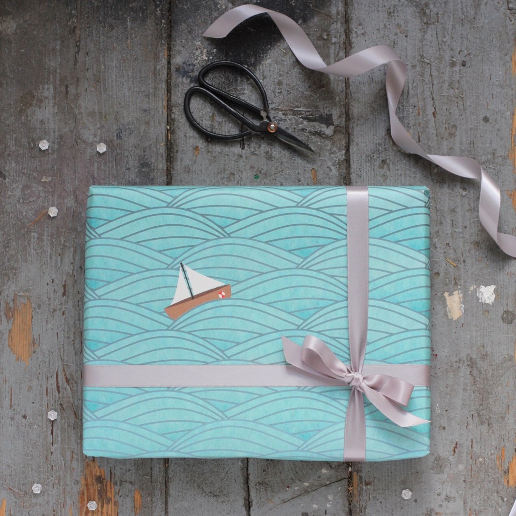 A gift wrapped in blue sailboat-print paper with a gray ribbon