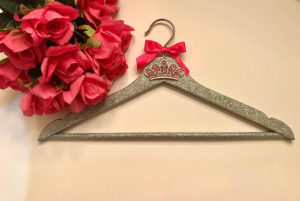 Glitter hanger with a red bow and small tiara charm next to red roses