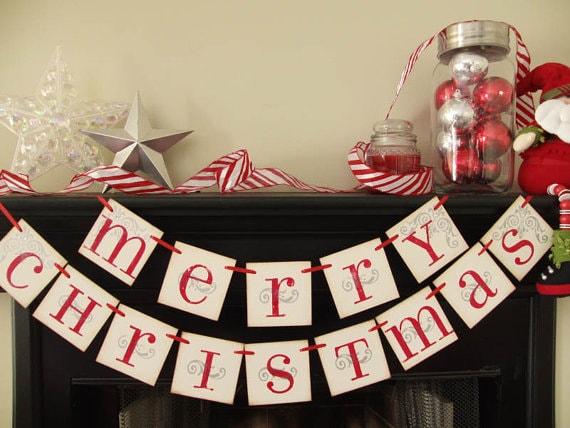 Merry Christmas paper banner and holiday ornaments displayed on a black fireplace mantel