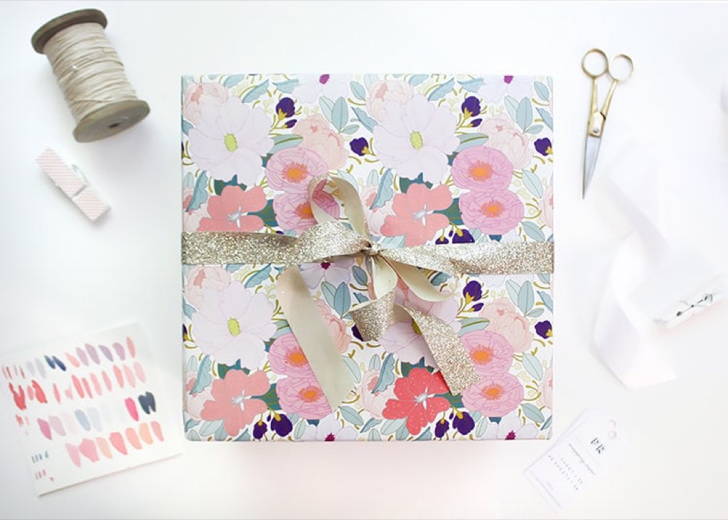 A gift wrapped in floral paper with a gold glitter ribbon